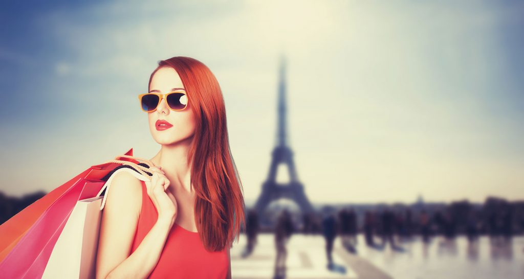 Woman standing in front of the eifel tower with shopping bags